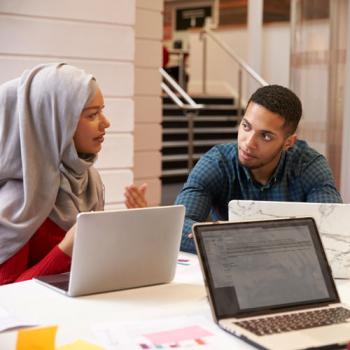 two teachers talking with laptops