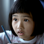 student with a pen and a questioning look on her face