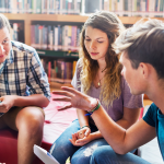 three students talking in library