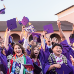 group of students in graduation gowns, throwing their caps